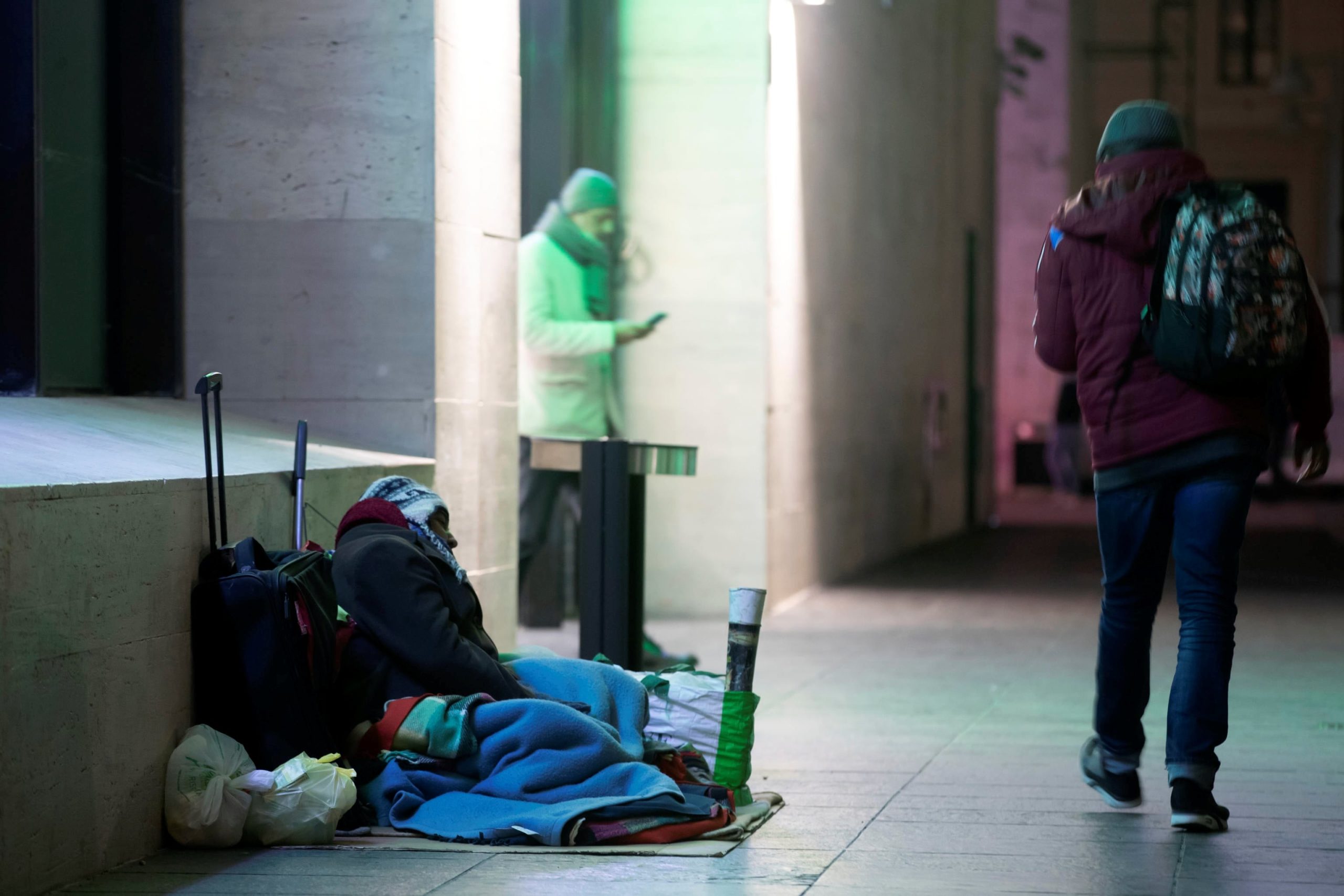 Un senzatetto prova a dormire appoggiandosi su una valigia