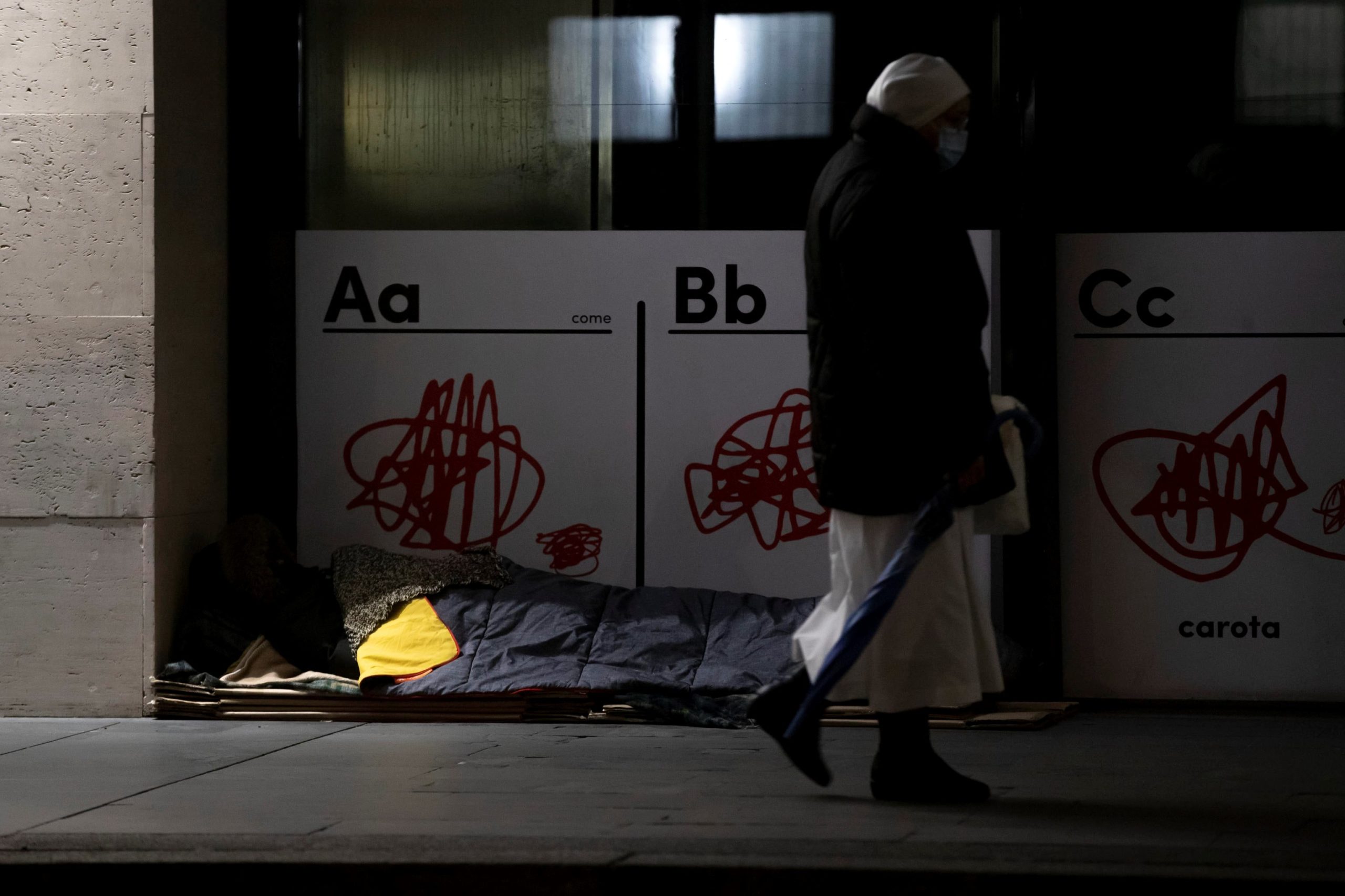 Un senzatetto si ripara davanti all'entrata di un negozio