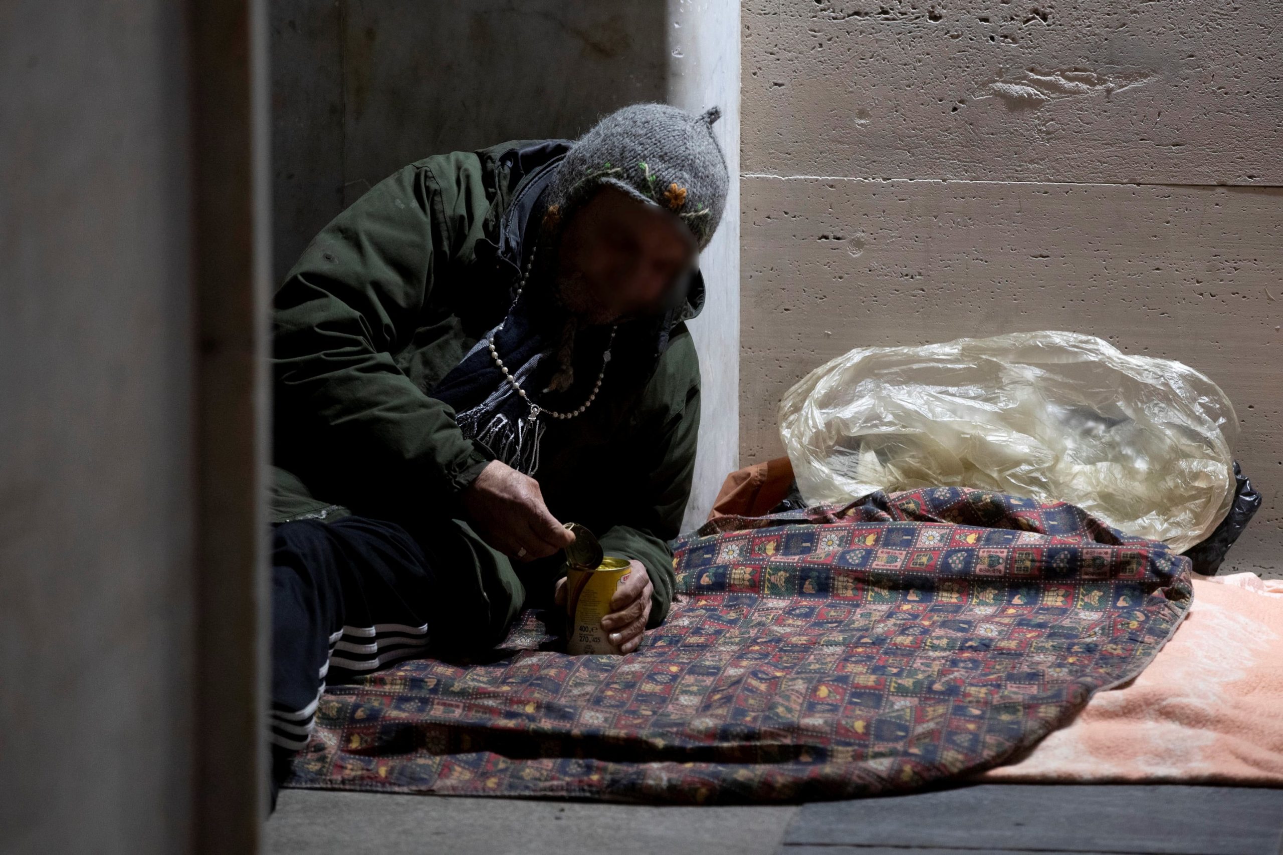 Un senzatetto apre una scatola per mangiare