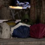 Un senzatetto si copre con degli ombrelli