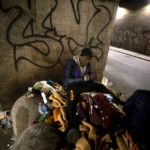 Due senzatetto seduti su un cumulo di immondizia