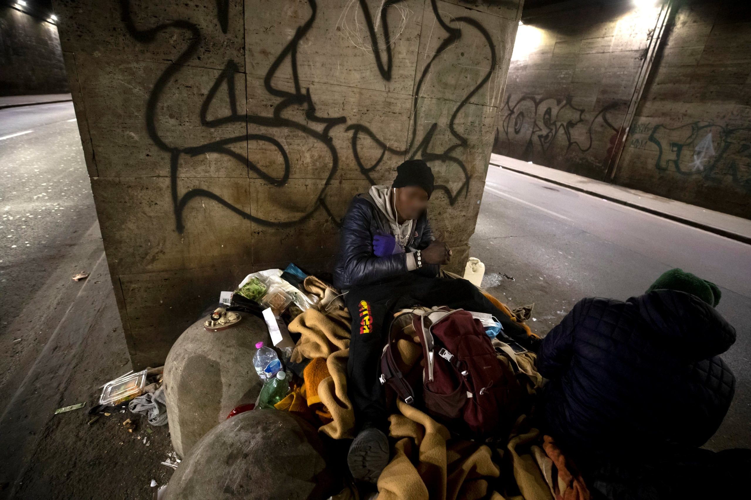 Due senzatetto seduti su un cumulo di immondizia