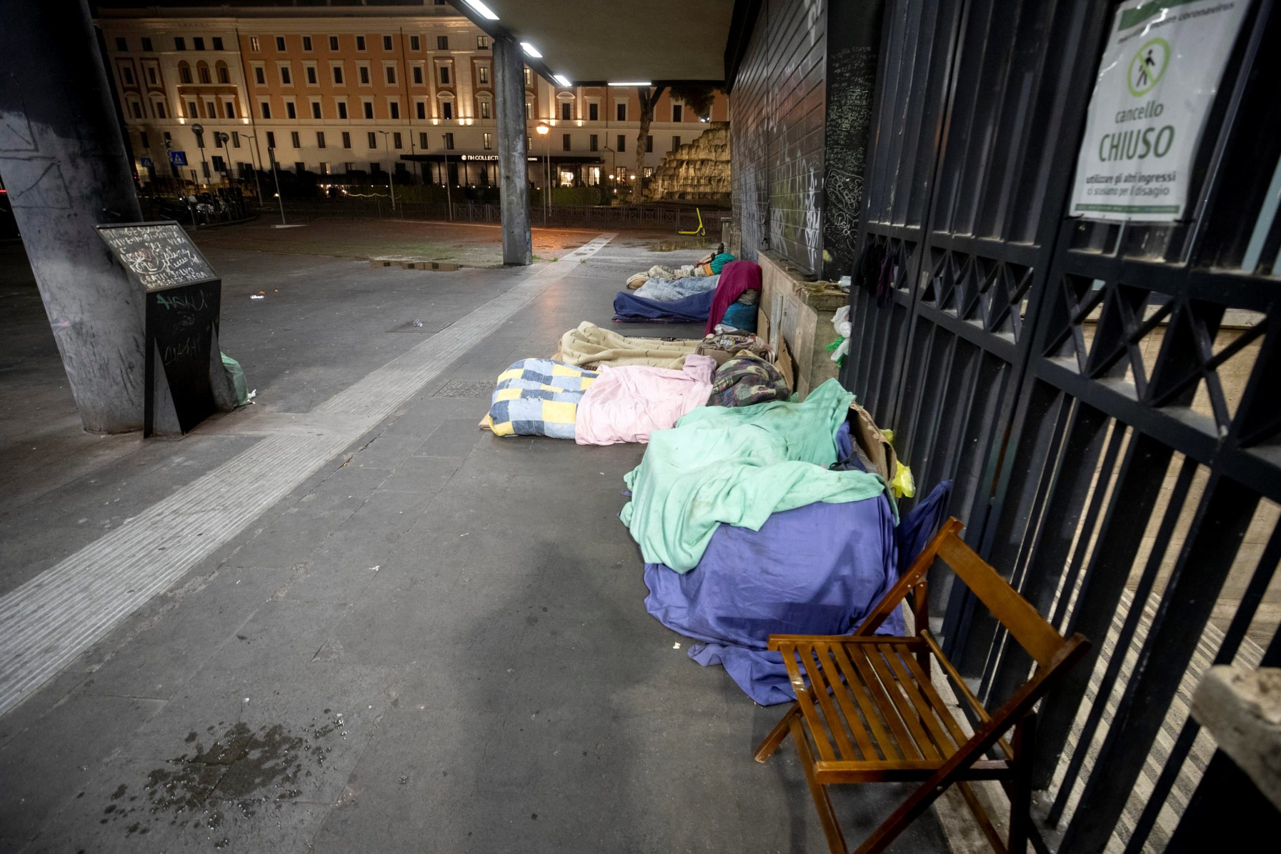 Alcuni senzatetto sdraiati sul marciapiede della stazione