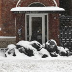 Un uomo ricoperto di neve sull'uscio di una casa
