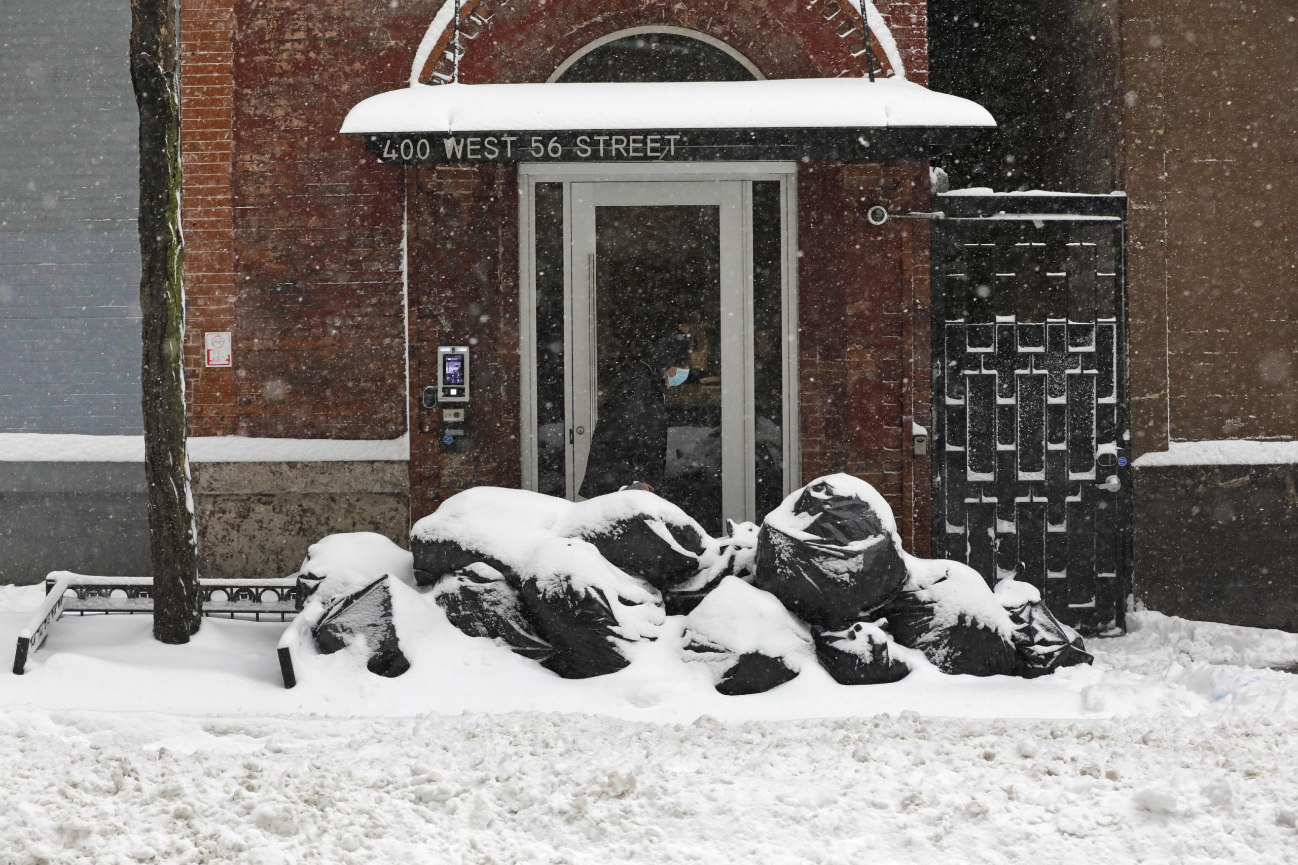 Un uomo ricoperto di neve sull'uscio di una casa