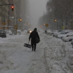 Un uomo cammina da solo per le strade innevate della città