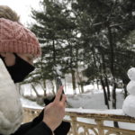 Una ragazza fotografa un piccolo pupazzo di neve