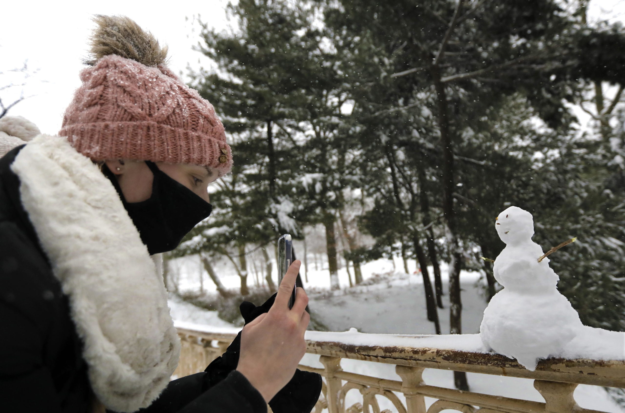 Una ragazza fotografa un piccolo pupazzo di neve
