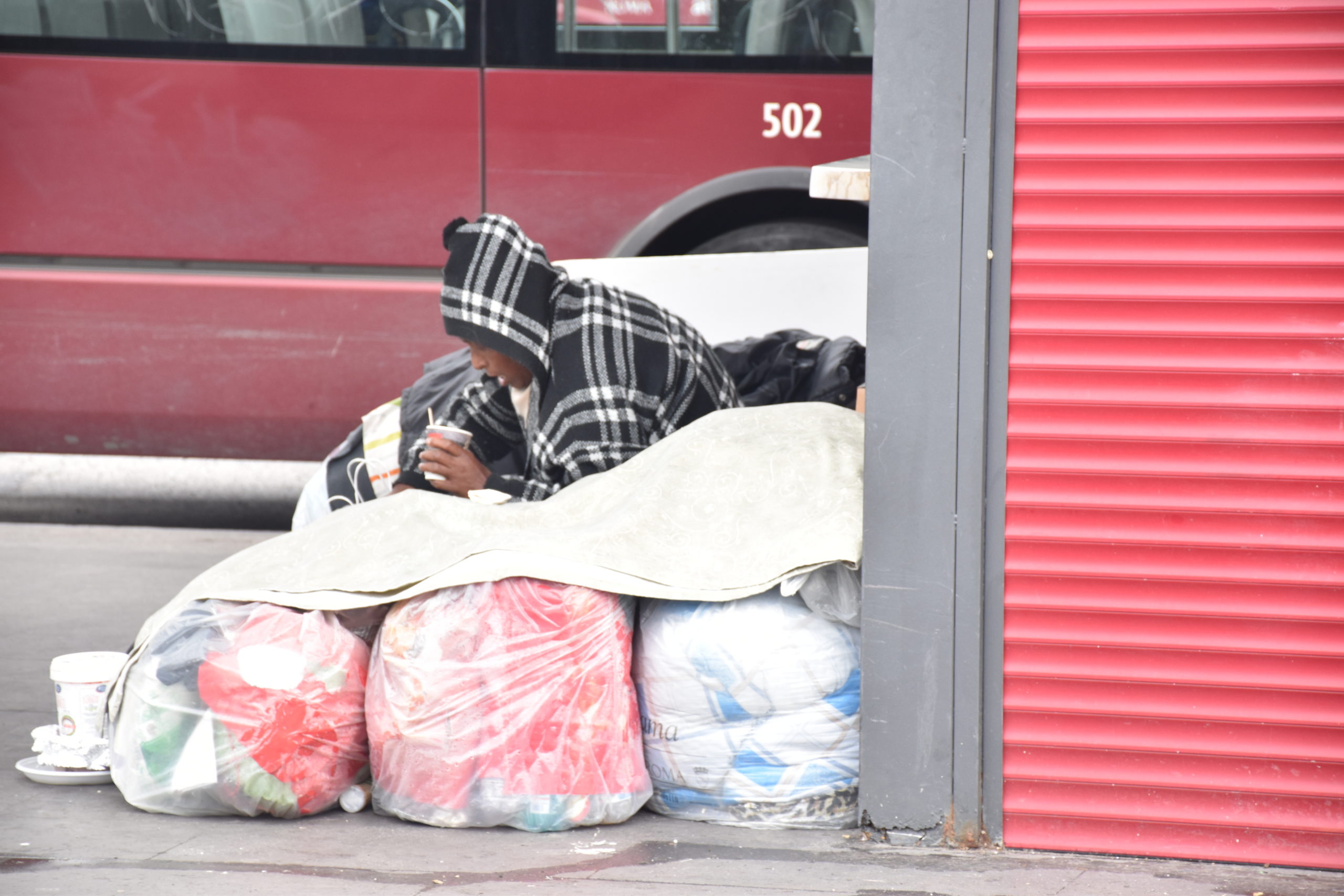 Un senzatetto si ripara dietro a un cumulo di rifiuti
