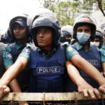 Gli agenti di polizia osservano dietro una barricata gli studenti Gli agenti di polizia osservano dietro una barricata gli studenti