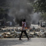 Un ragazzo cammina tra le barricate durante gli scontri a Yangon Un ragazzo cammina tra le barricate durante gli scontri a Yangon