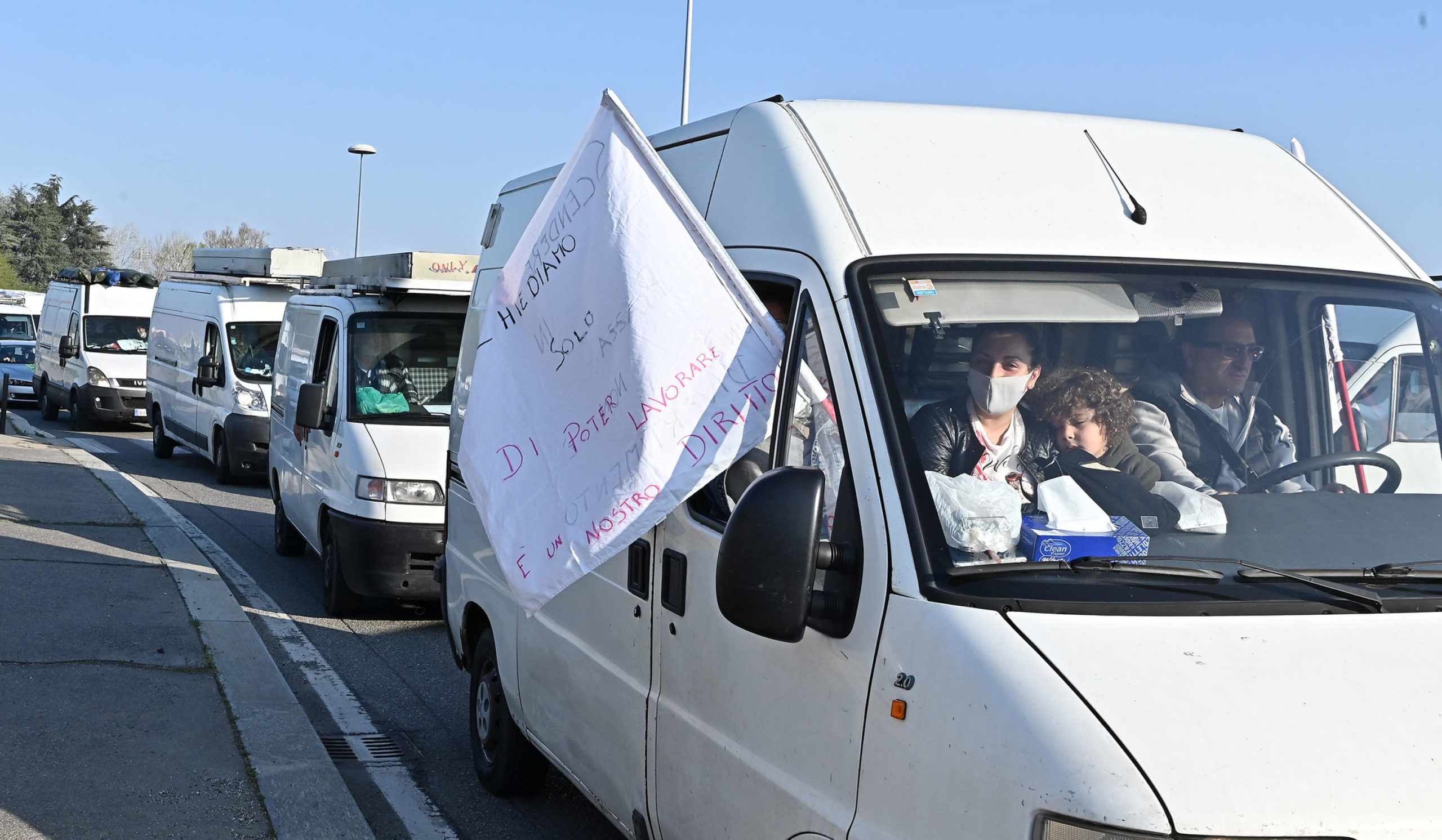 Gli ambulanti nel traffico con bandiere di protesta