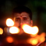 Il volto di un sacerdote induista dietro le luci delle piccole fiaccole