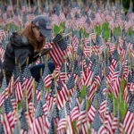 Una donna posiziona una bandiera americana in un giardino commemorativo