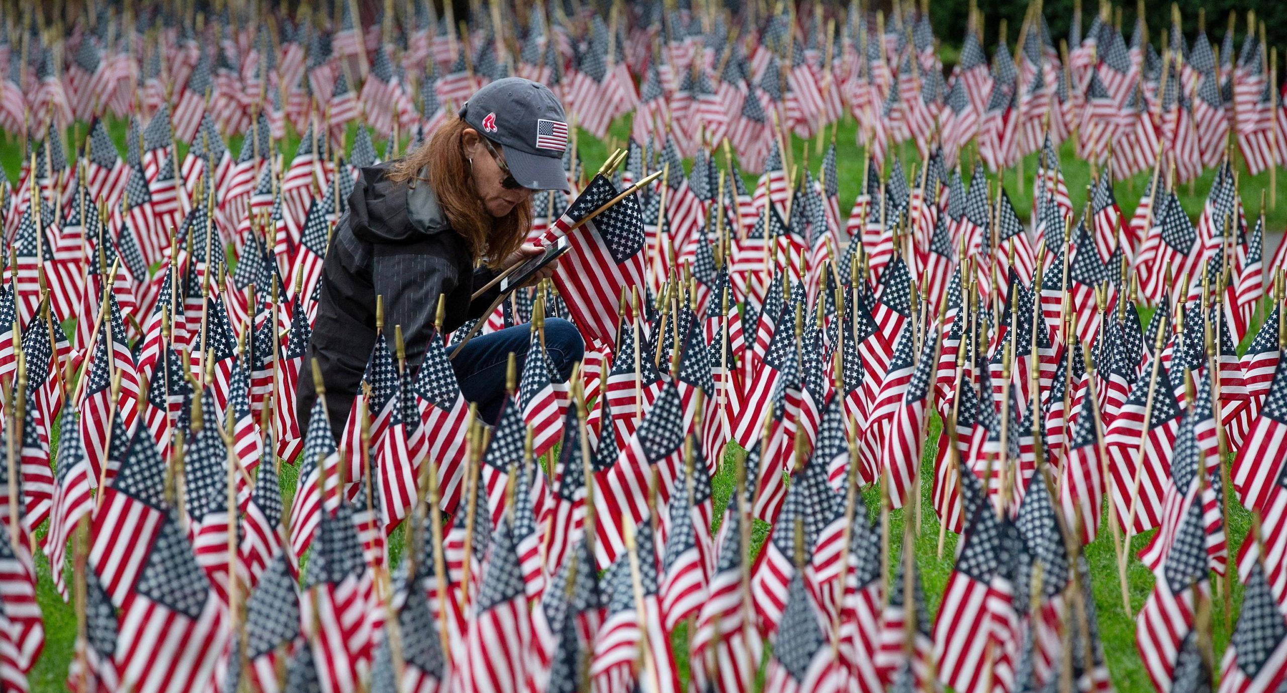 Una donna posiziona una bandiera americana in un giardino commemorativo Una donna posiziona una bandiera americana in un giardino commemorativo
