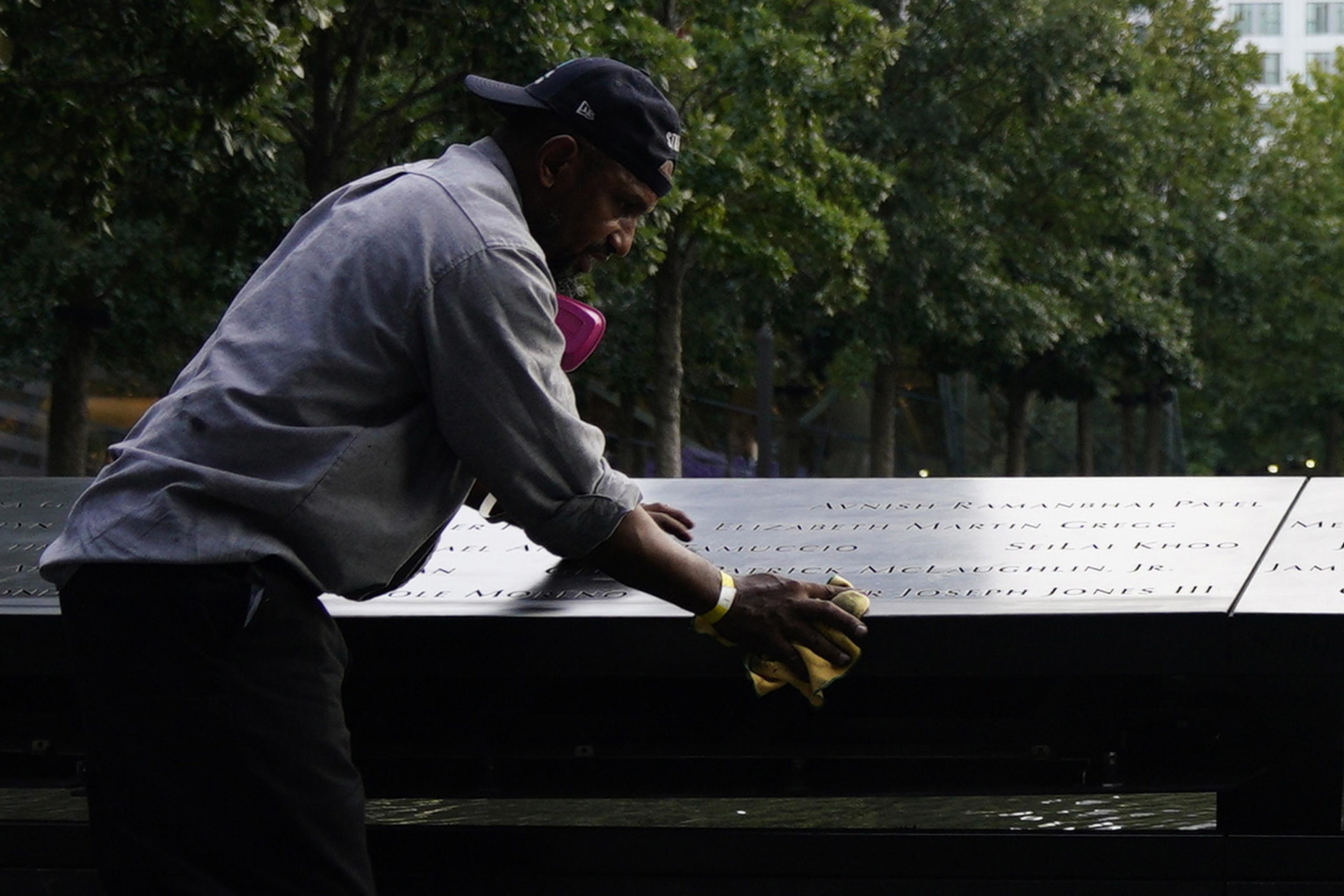 Un inserviente pulisce le targhe attorno alle fontane commemorative dell'11 settembre a New York Un inserviente pulisce le targhe attorno alle fontane commemorative dell'11 settembre a New York