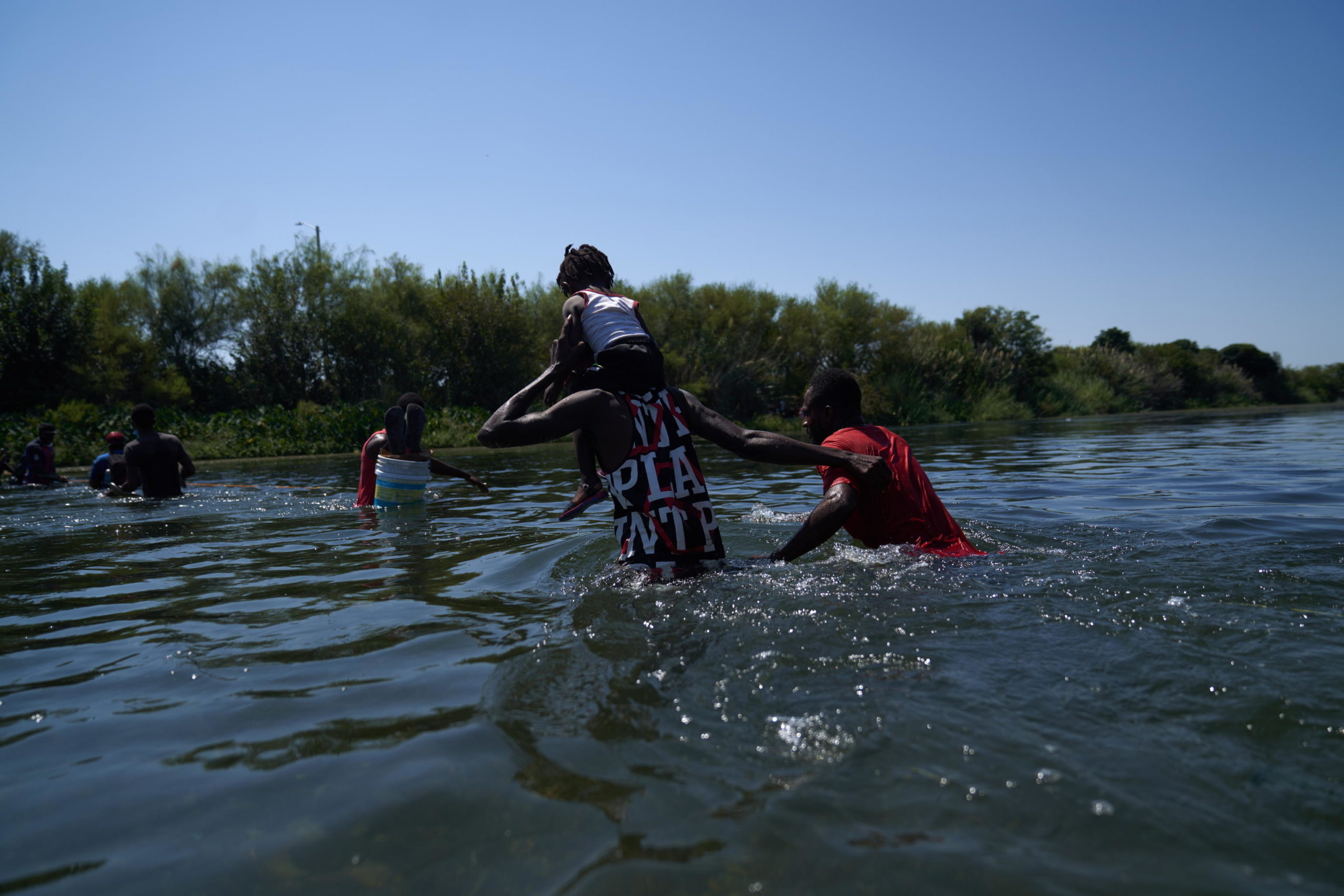 Un padre attraversa il fiume con la propria figlia sulle spalle Un padre attraversa il fiume con la propria figlia sulle spalle