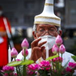 Un monaco buddista prepara le candele in vista della processione mattutina Un monaco buddista prepara le candele in vista della processione mattutina