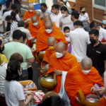 I devoti buddisti offrono candele e fiori durante il rituale dell'elemosina mattutina I devoti buddisti offrono candele e fiori durante il rituale dell'elemosina mattutina