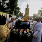 Devoti buddisti offrono candele e fiori per il rito delle offerte