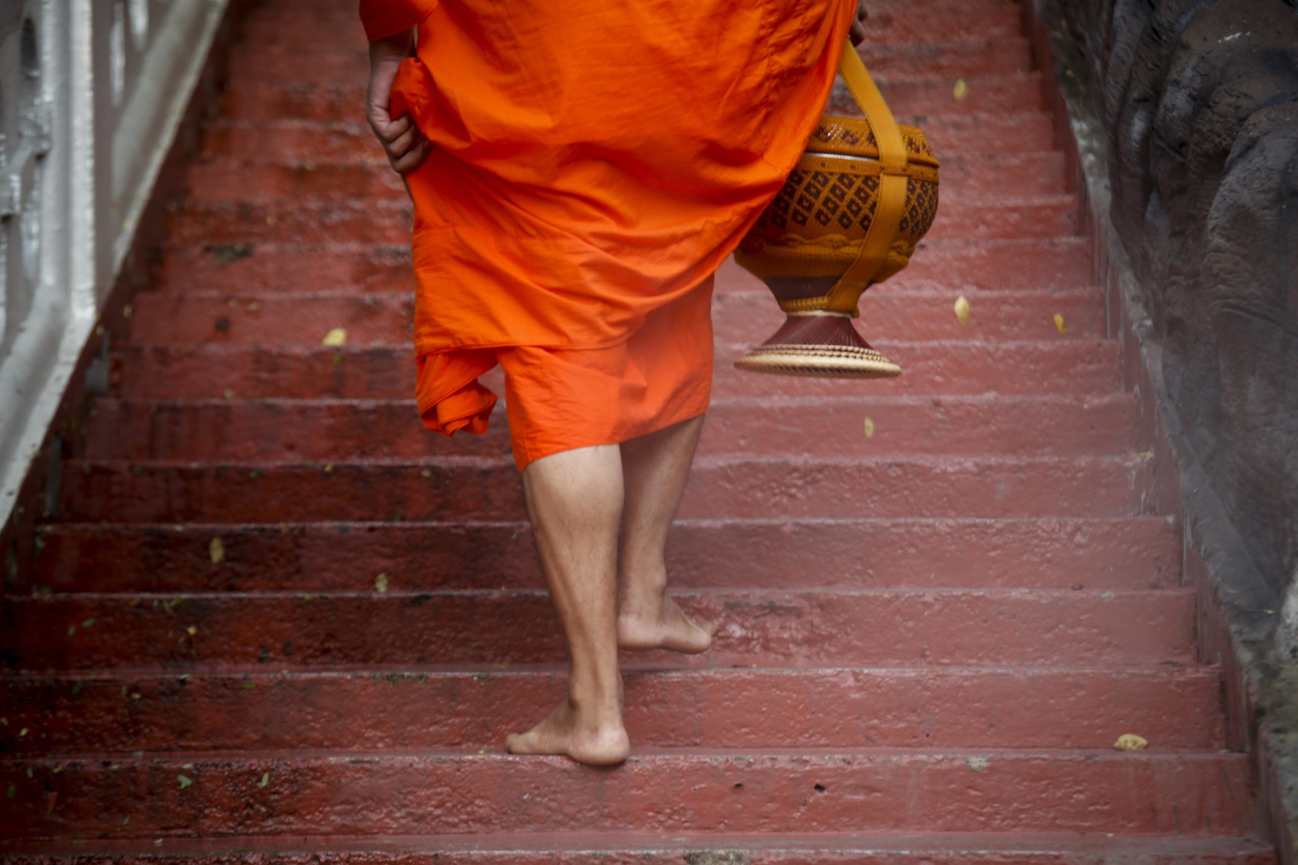 Un monaco buddista con la sua ciotola durante il rituale dell'elemosina mattutina Un monaco buddista con la sua ciotola durante il rituale dell'elemosina mattutina