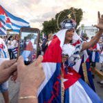 Una donna mascherata sostiene la protesta del popolo cubano contro il governo di Cuba a Miami, in Florida