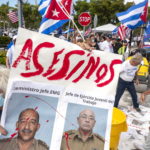 Alcuni manifestanti mostrano un cartello con scritto 'assassini' durante la protesta a supporto del popolo cubano contro il governo di Cuba a Miami, in Florida