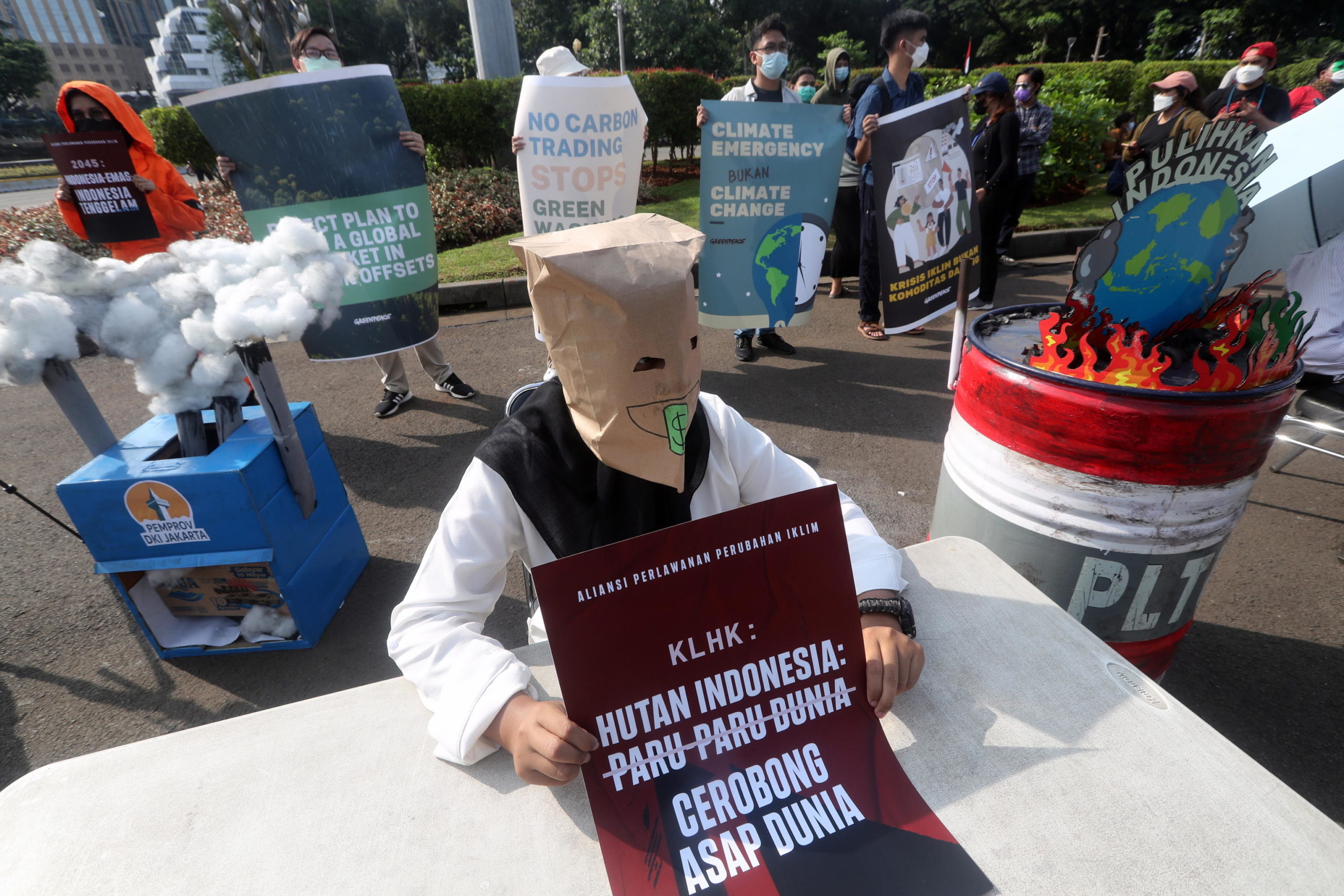 Un'attivista indonesiana indossa una maschera di protesta e tiene il suo poster che recita "Le foreste dell'Indonesia non sono i polmoni del mondo, ma i camini del mondo"