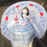 Un'attivista indonesiana indossa un vestito con la scritta "Chiudere le centrali a carbone" mentre si sdraia in strada durante la manifestazione a Giacarta