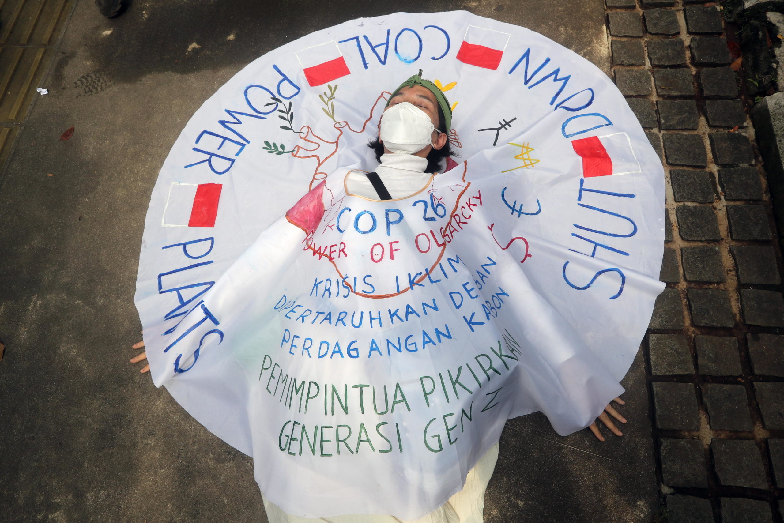 Un'attivista indonesiana indossa un vestito con la scritta "Chiudere le centrali a carbone" mentre si sdraia in strada durante la manifestazione a Giacarta