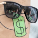 Gli occhiali di un attivista indonesiano mascherato riflettono la manifestazione in corso a Giacarta