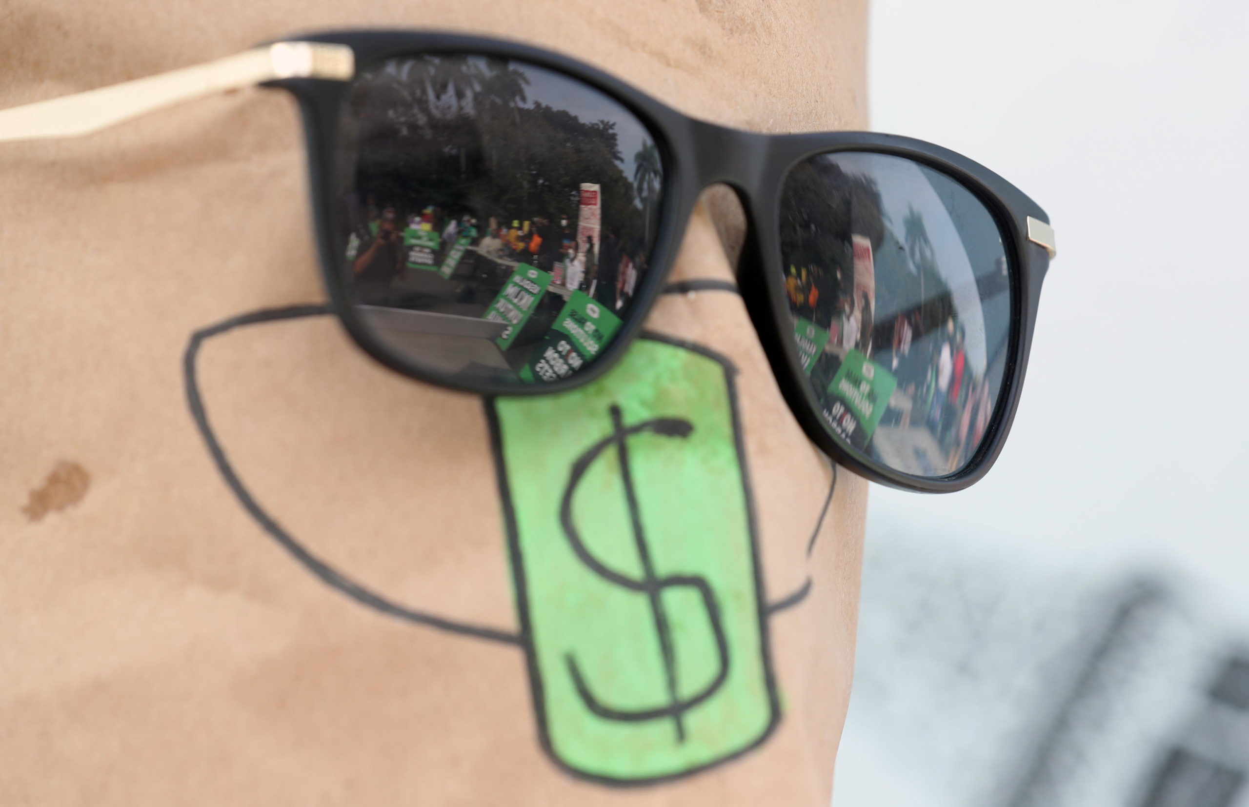 Gli occhiali di un attivista indonesiano mascherato riflettono la manifestazione in corso a Giacarta