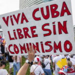 Un cartello chiede Cuba libera senza il comunismo. Sullo sfondo la manifestazione contro il governo cubano a Miami, in Florida