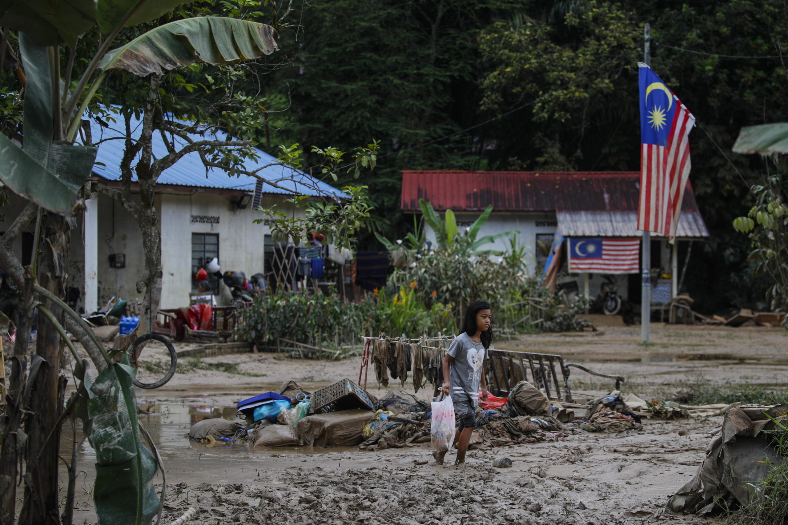 Una bambina raccoglie poche cose dalla sua abitazione inagibile a causa del fango