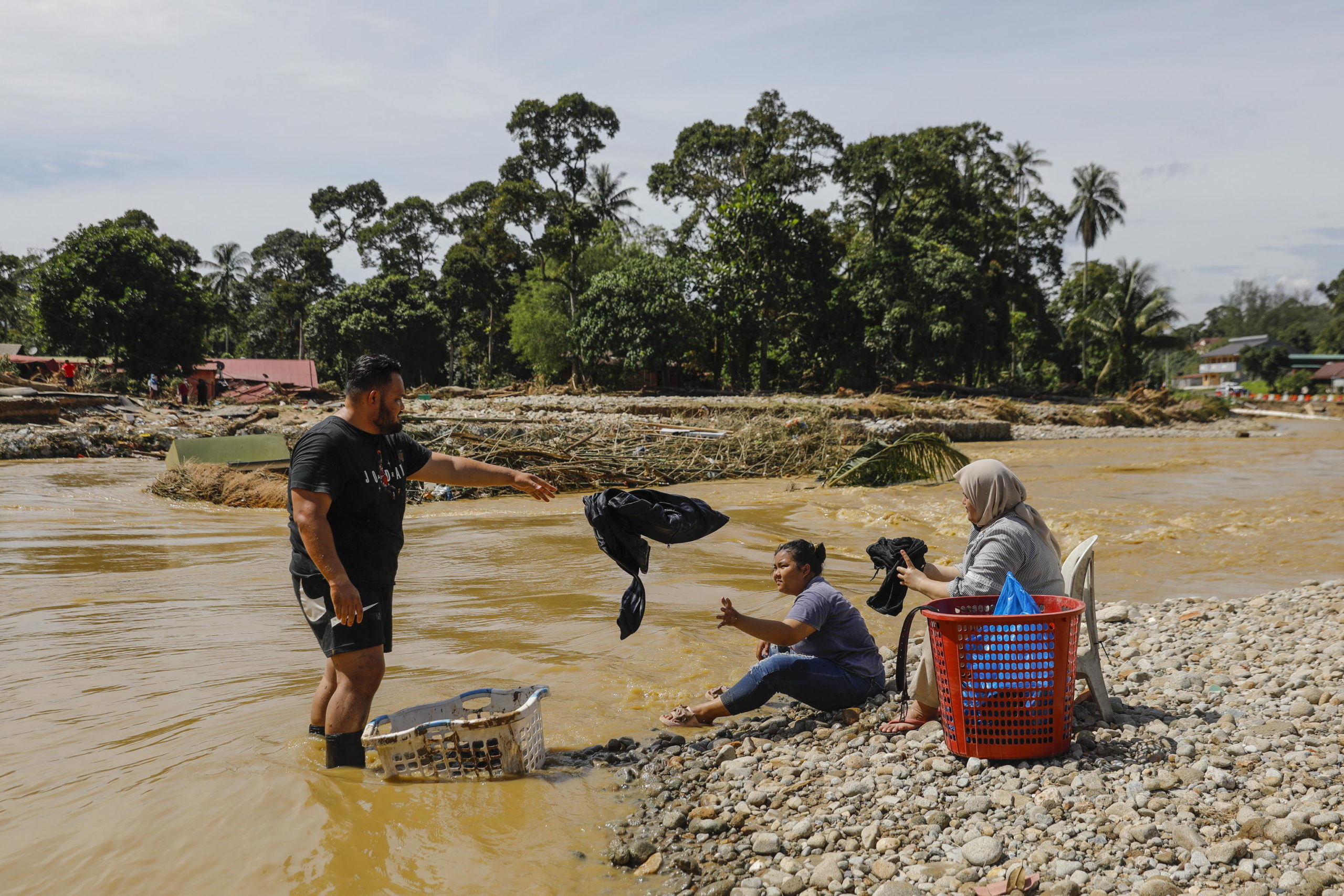 Uomini e donne utilizzano il fiume per lavare i panni dopo che le forniture di acqua ed elettricità sono state tagliate a seguito dell'inondazione