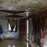 Un uomo pulisce la sua casa ricoperta di fango dopo l'alluvione