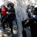 Gli agenti si difendono dai colpi dei migranti haitiani