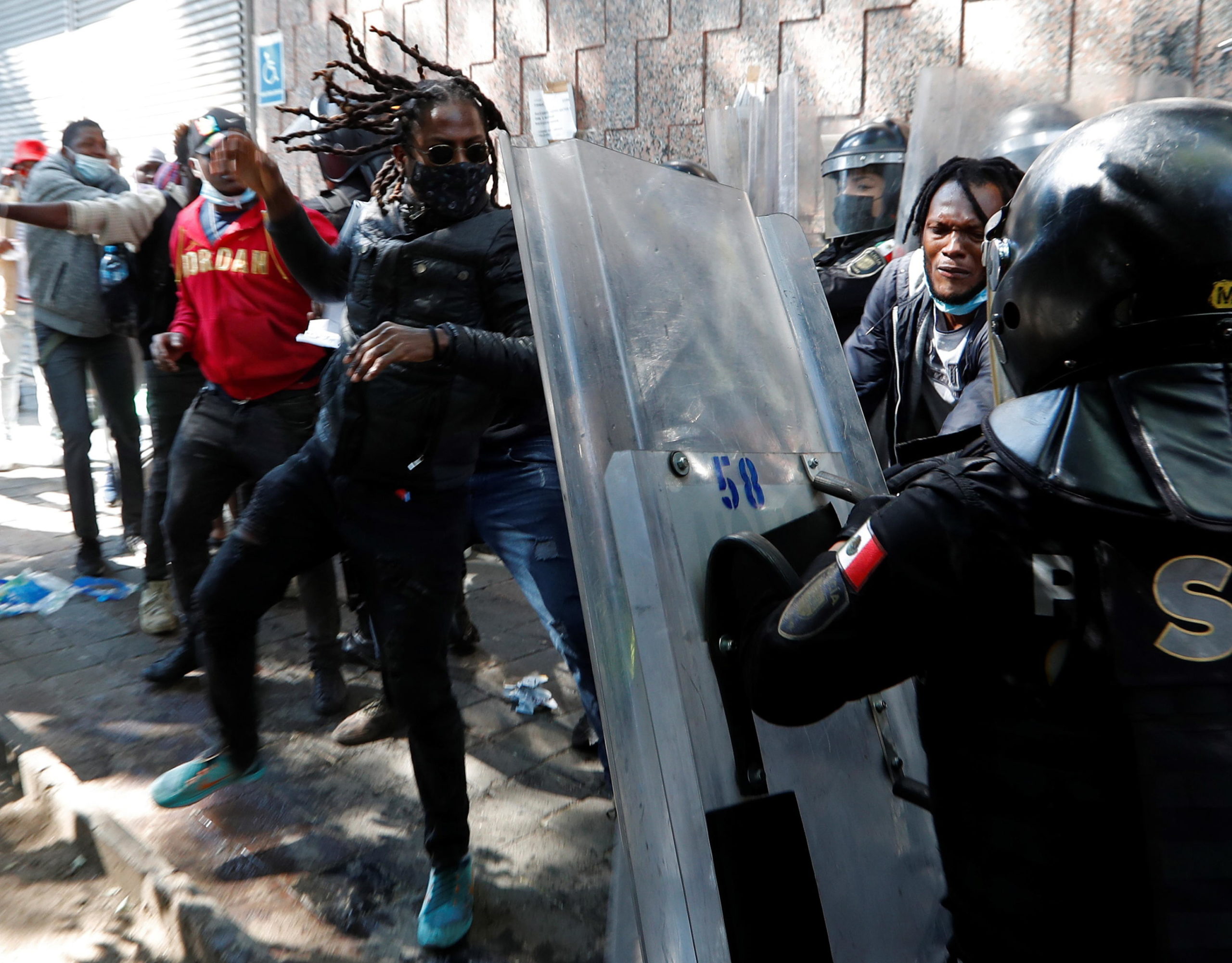 Gli agenti si difendono dai colpi dei migranti haitiani