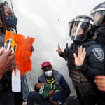 Un uomo mostra un cartello per chiedere la regolarizzazione del proprio status