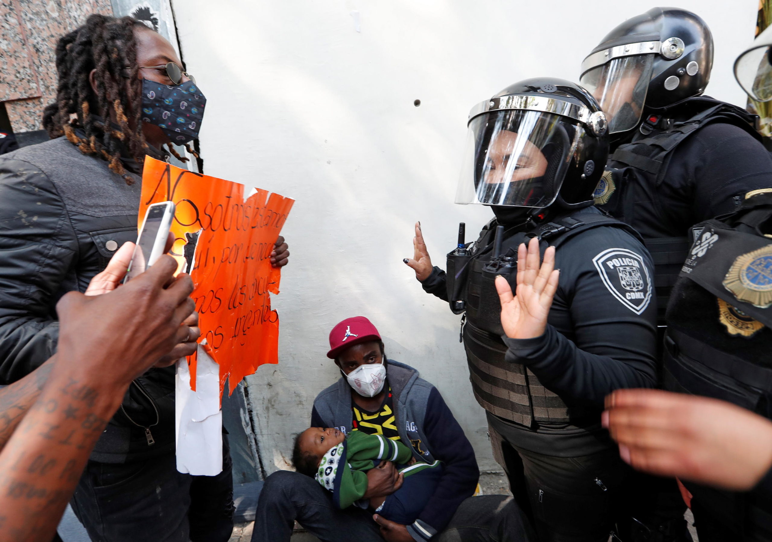 Un uomo mostra un cartello per chiedere la regolarizzazione del proprio status