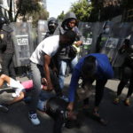 Un uomo e una donna soccorrono una manifestante rimasta ferita negli scontri