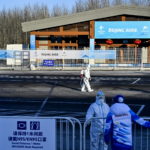 Operatori in tuta hazmat disinfettano la strada Operatori in tuta hazmat disinfettano la strada