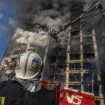 Un vigile del fuoco guarda il fumo che esce dall'edificio devastato dalle bombe Un vigile del fuoco guarda il fumo che esce dall'edificio devastato dalle bombe
