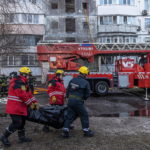 Due vigili del fuoco trasportano una delle due vittime del bombardamento Due vigili del fuoco trasportano una delle due vittime del bombardamento