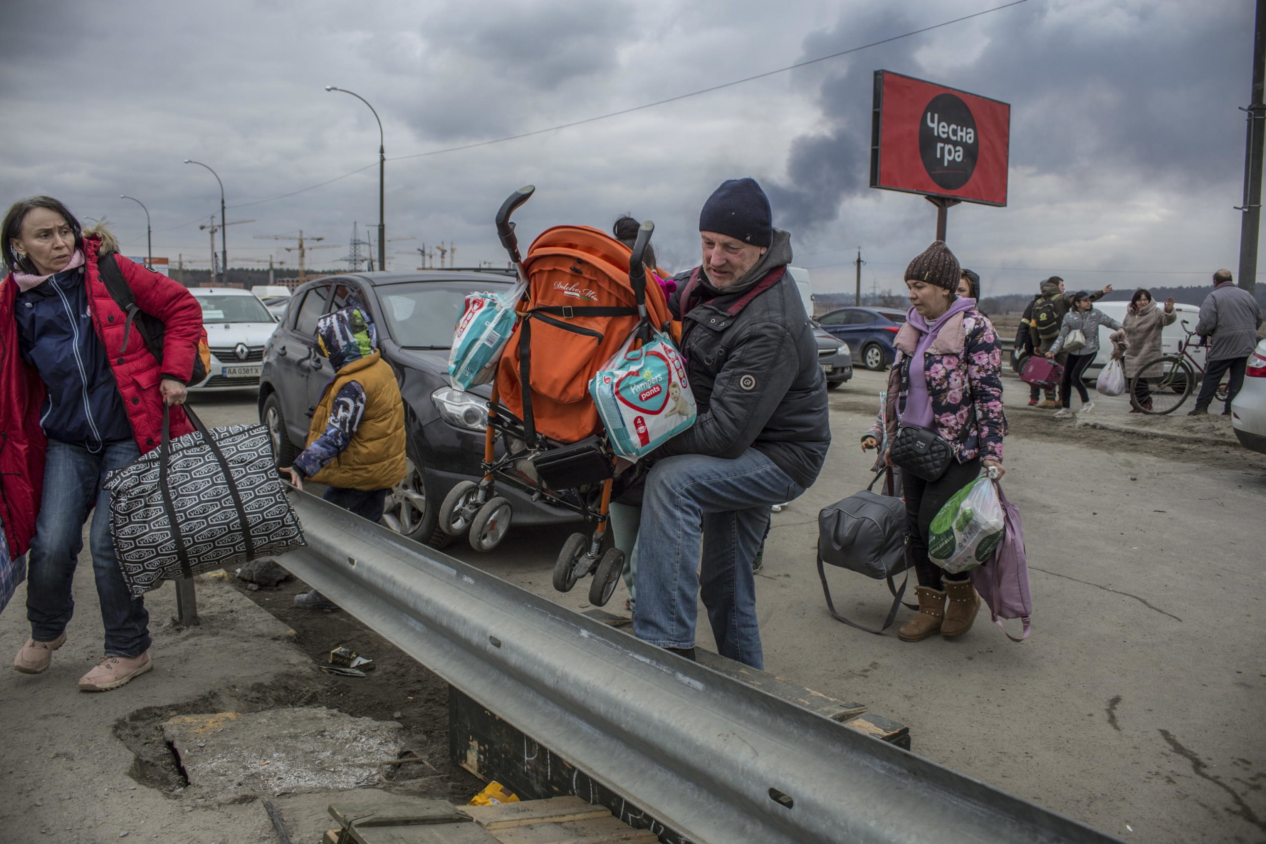 I civili attraversano le macerie di un ponte danneggiato nella città di Irpin vicino a Kiev