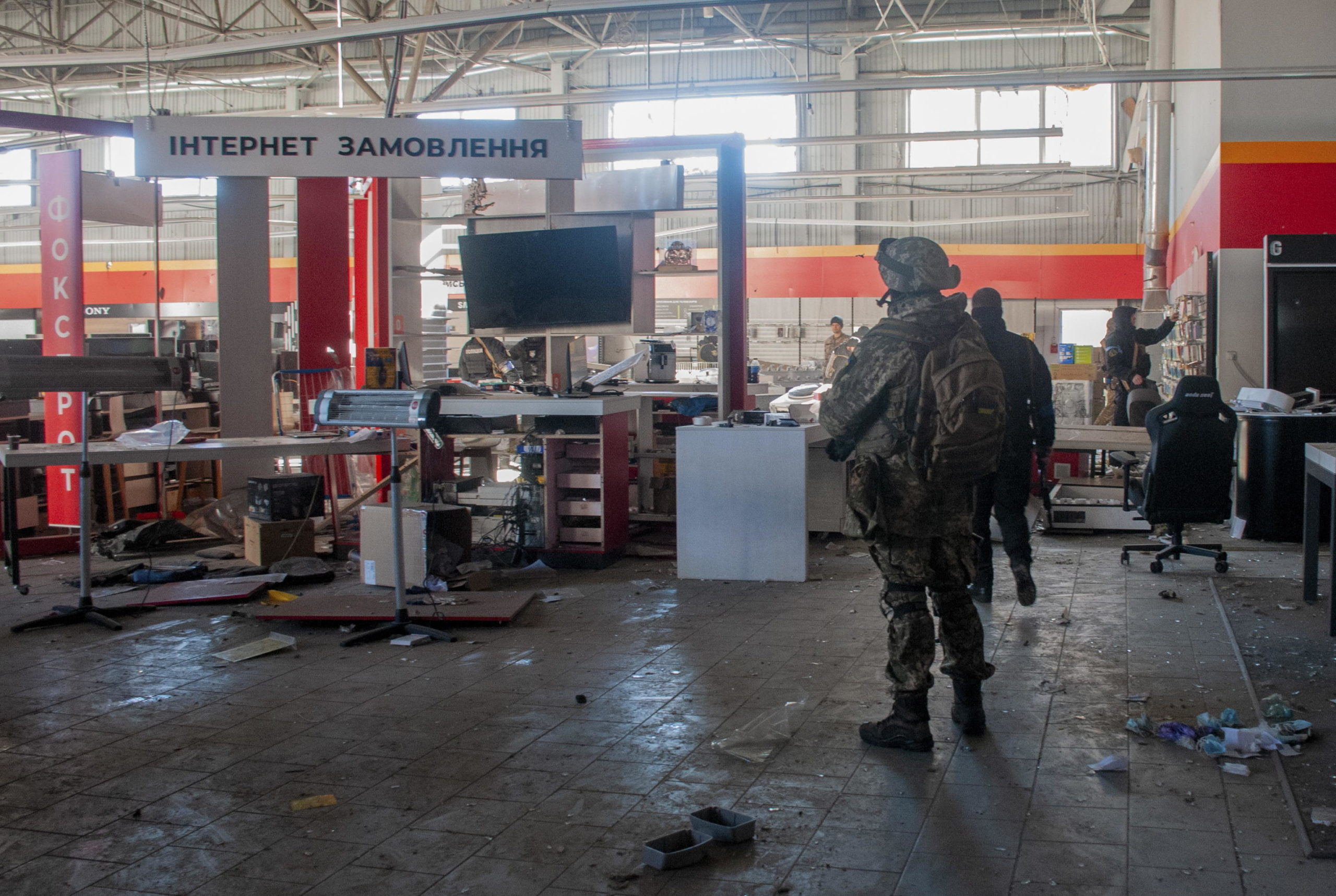 Poliziotti ucraini e militari del Comando di difesa territoriale trasportano merci da un negozio danneggiato per metterle al sicuro dopo i bombardamenti a Kharkiv
