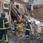 I soccorritori e i vigili del fuoco intenti a rimuovere le macerie del palazzo distrutto a Kharkiv.