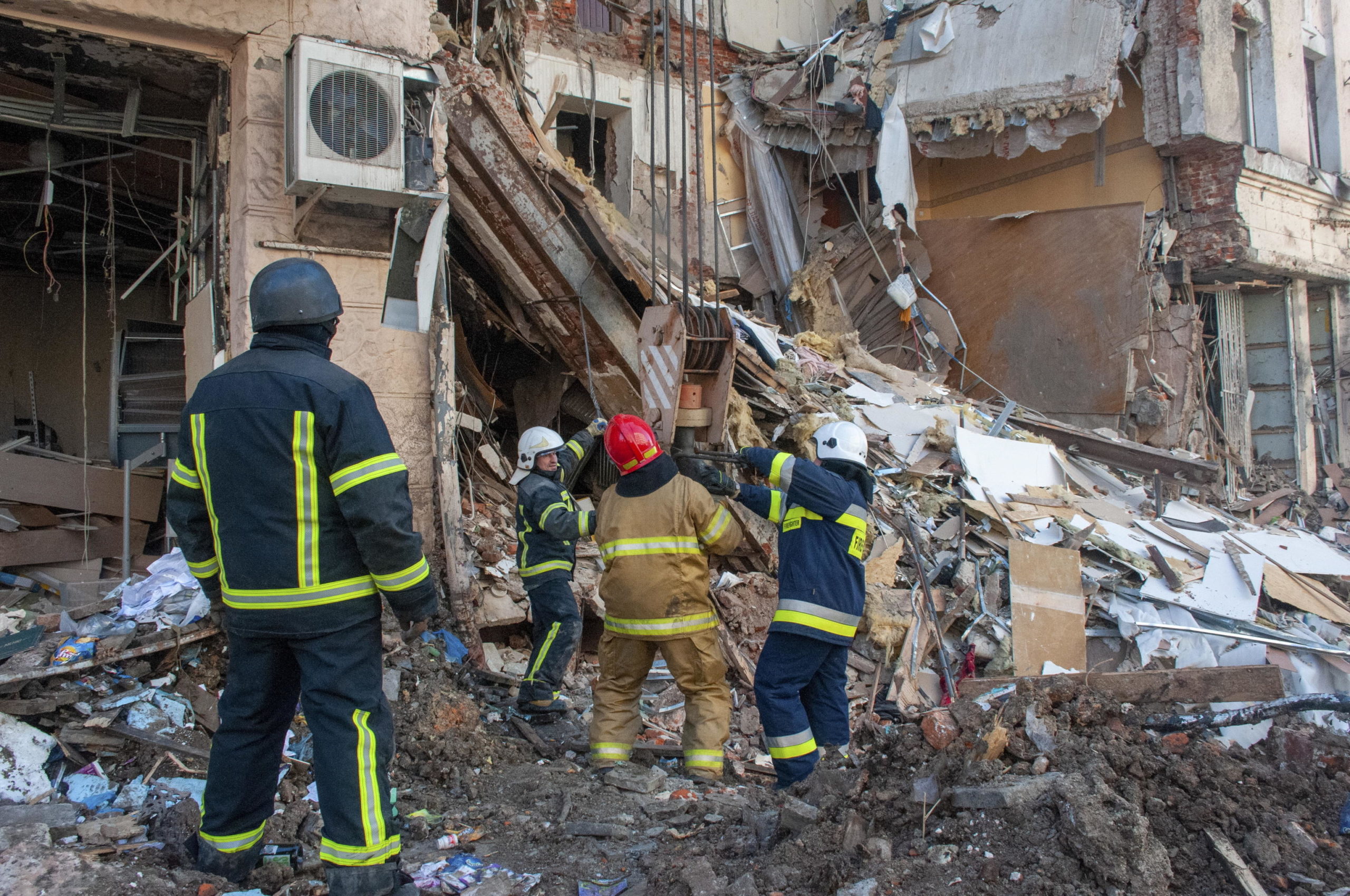 I soccorritori e i vigili del fuoco intenti a rimuovere le macerie del palazzo distrutto a Kharkiv.