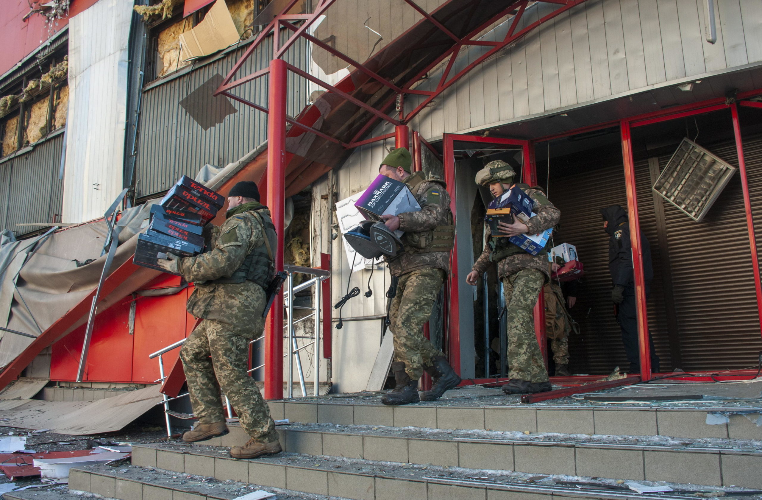 Poliziotti ucraini e militari del Comando di difesa territoriale trasportano merci da un negozio danneggiato per metterle al sicuro dopo i bombardamenti a Kharkiv