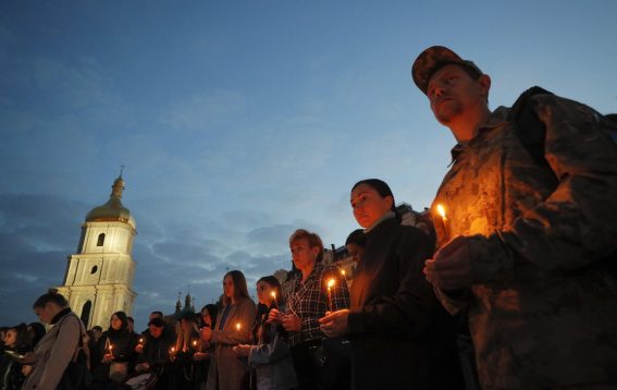 Persone reggono candele accese nel corso della manifestazione in ricordo delle vittime del centro di Olenivka